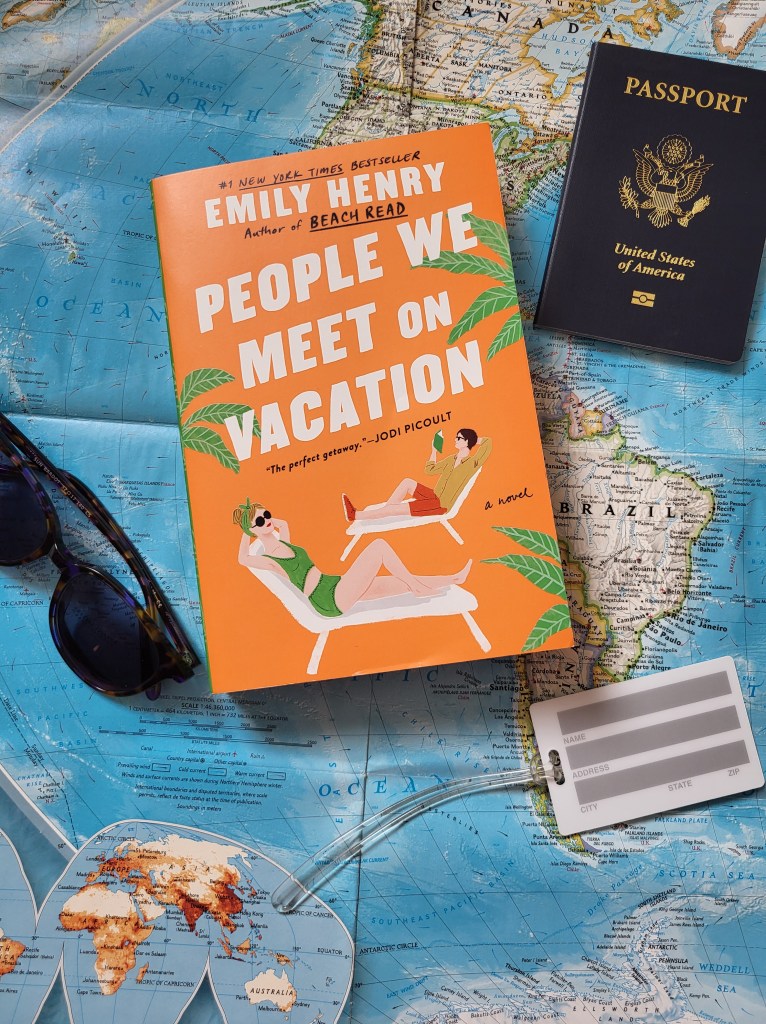 photo of People We Meet on Vacation: the cover depicts an illustration of a man and woman in lounge chairs on an orange background with palm trees. The book itself sits on a map, surrounded by a passport, sunglasses, and a luggage tag.