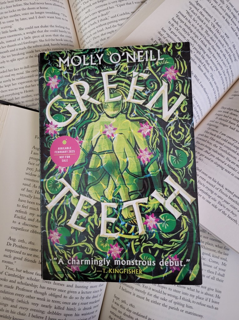 photo of Greenteeth: the cover depicts lake plants surrounding a green female figure, legs curled up and hair flowing outward. Pink flowers dot the green plants.