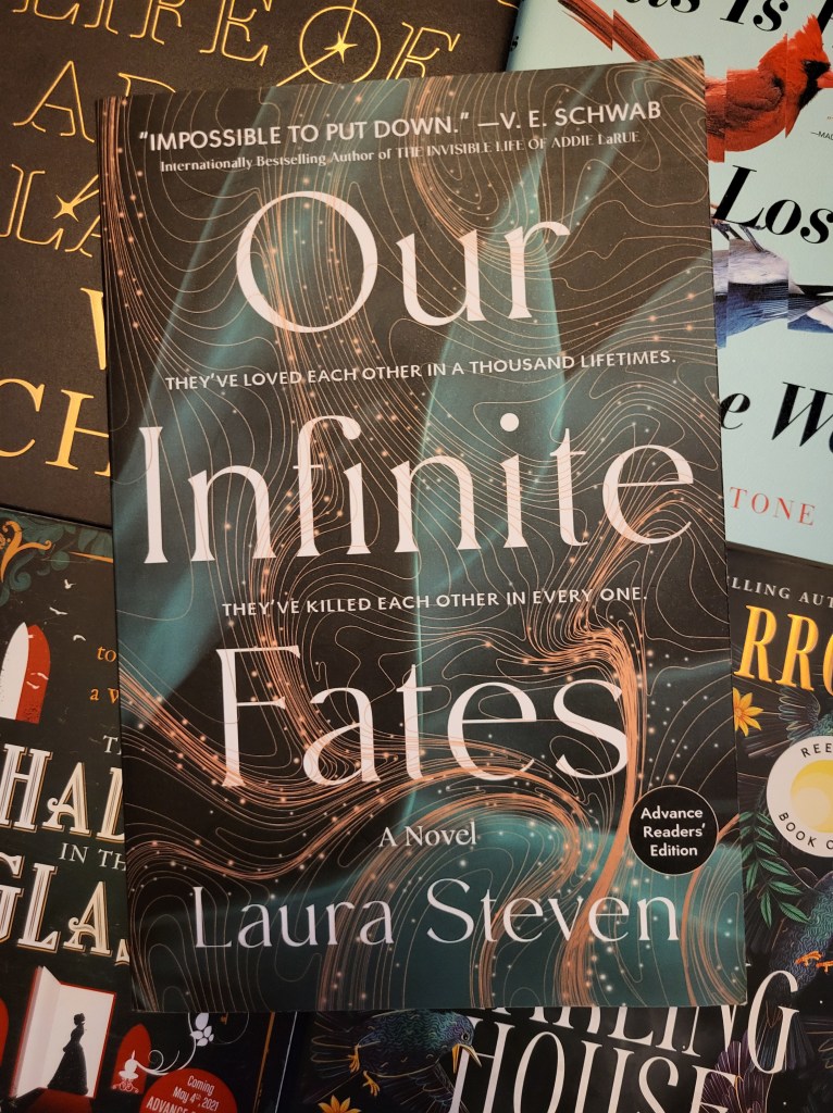 photo of Our Infinite Fates: a black background, on which teal and gold lines swirl in random twists. The cover and author's name are written in white, and there are the words: "they've loved each other in a thousand lifetimes. They've killed each other in every one."