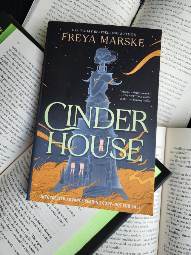 photo of Cinder House: a dark star-filled sky serves as the background. The foreground is a gray house, which also forms a young woman's body. Orange flames lick at the base of the house.
